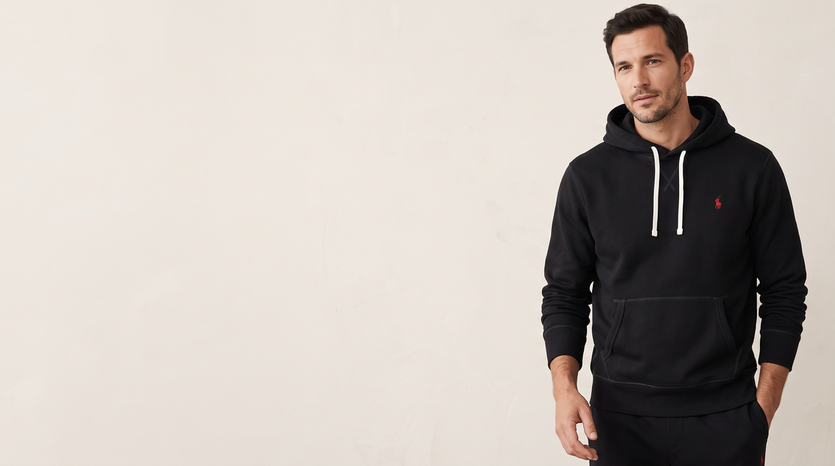 Man in a black Ralph Lauren-style hoodie in a warm off-white studio