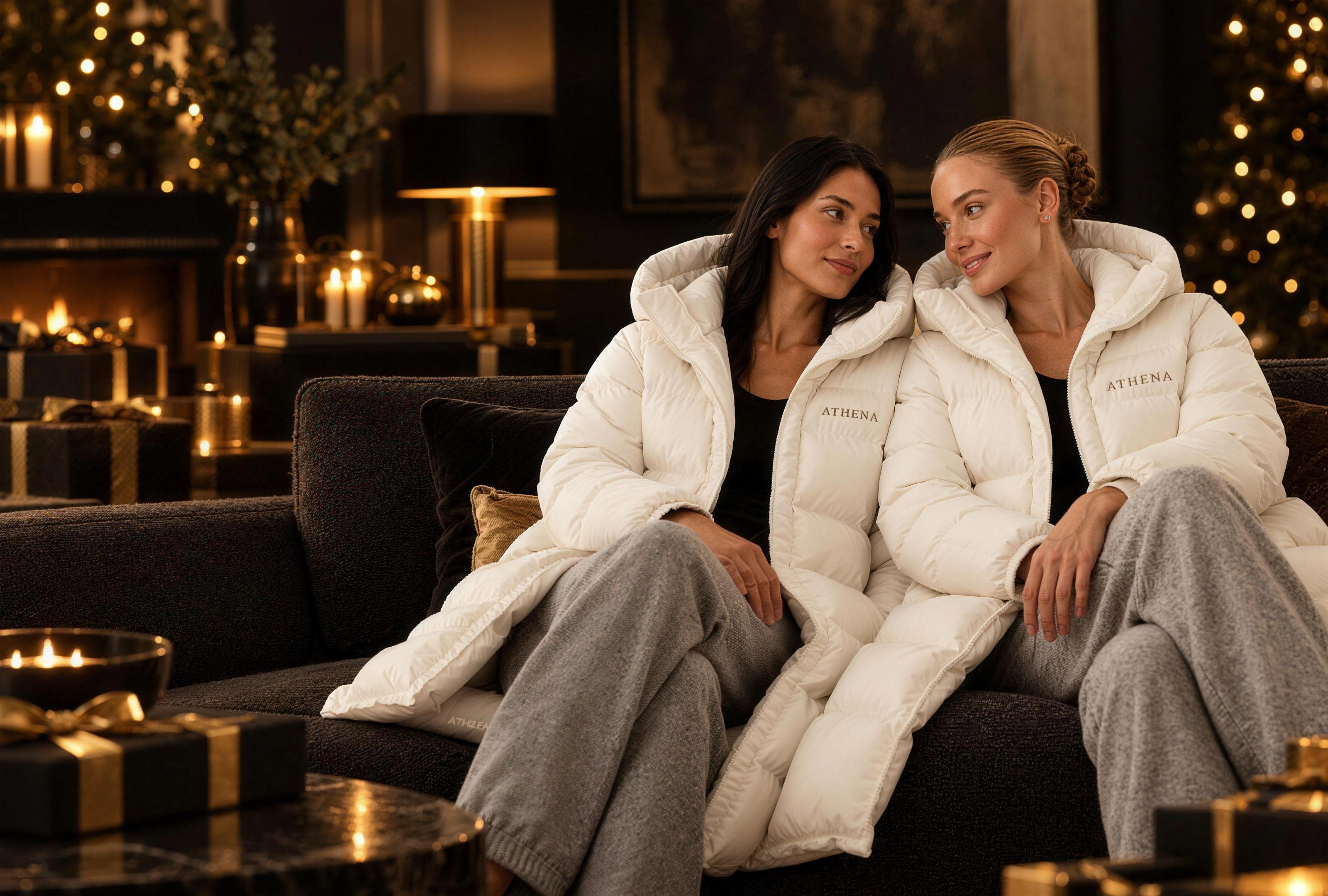 Two women relaxing on a sofa in cream ATHENA puffer coats