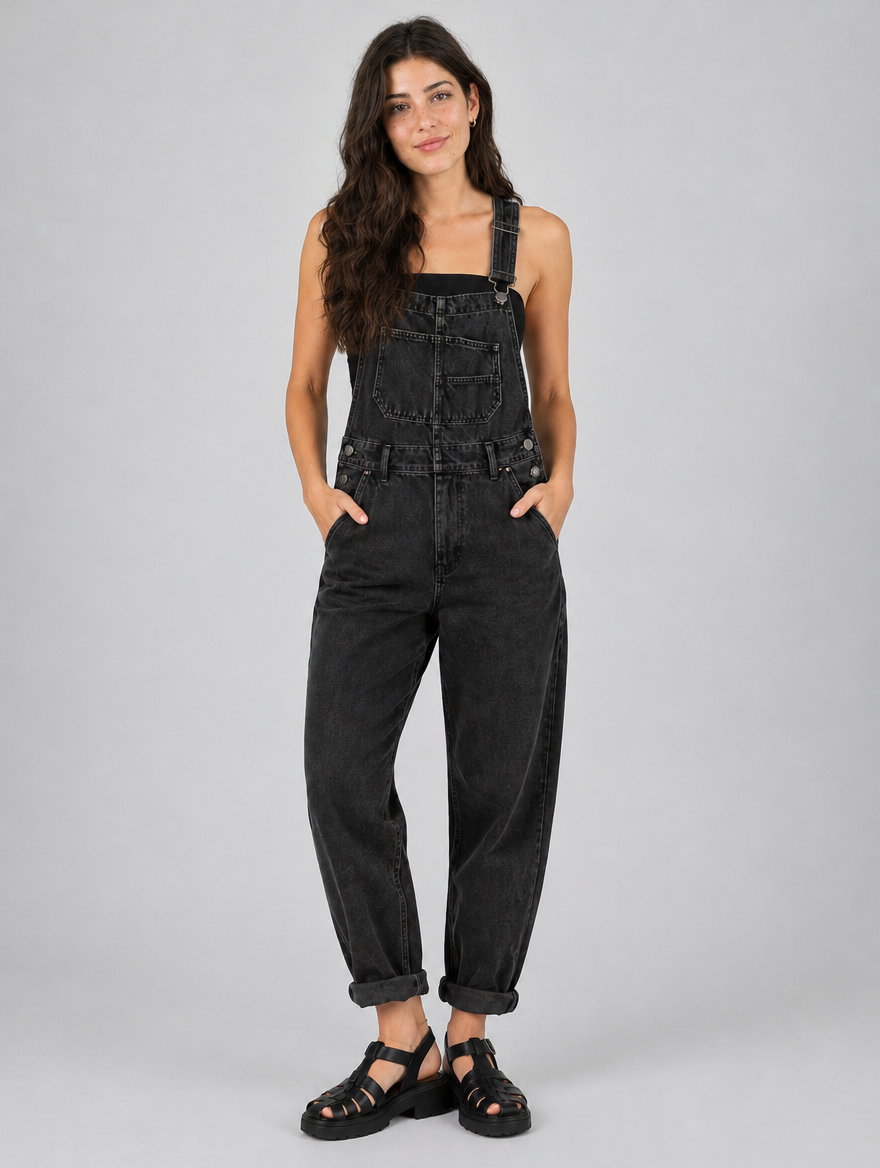Woman wearing black loose fit denim overalls, front view