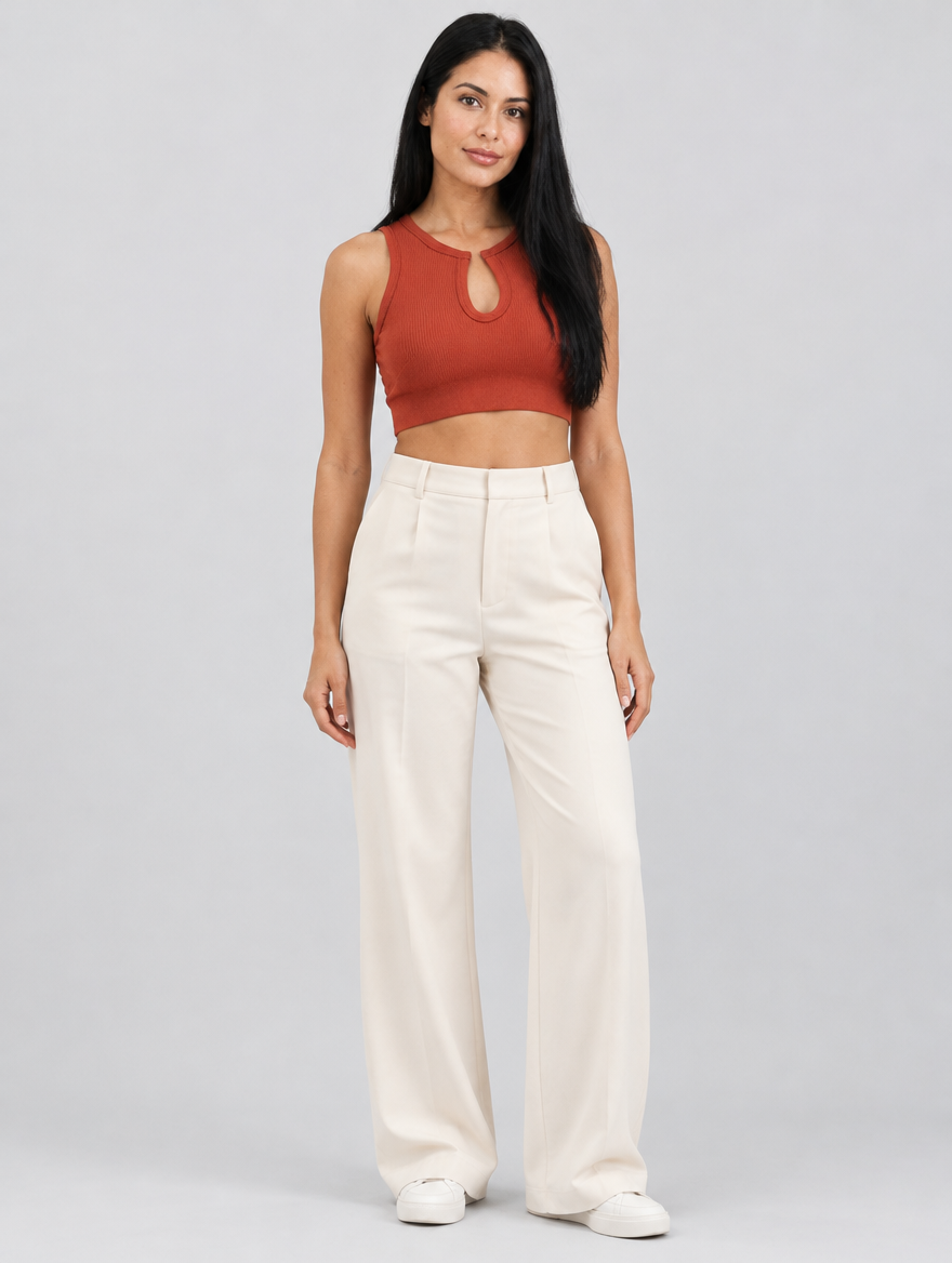 Woman wearing a rust orange ribbed crop top with keyhole front and cream trousers, front view