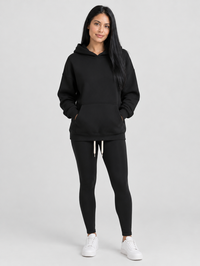 Woman wearing a black pullover hoodie with front pocket and drawstring, front view