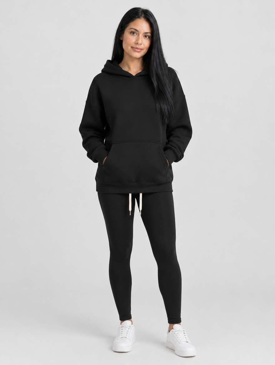 Woman wearing a black pullover hoodie with front pocket and drawstring, front view