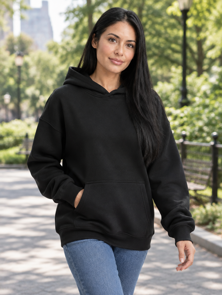 Black pullover hoodie styled with jeans, walking in a park