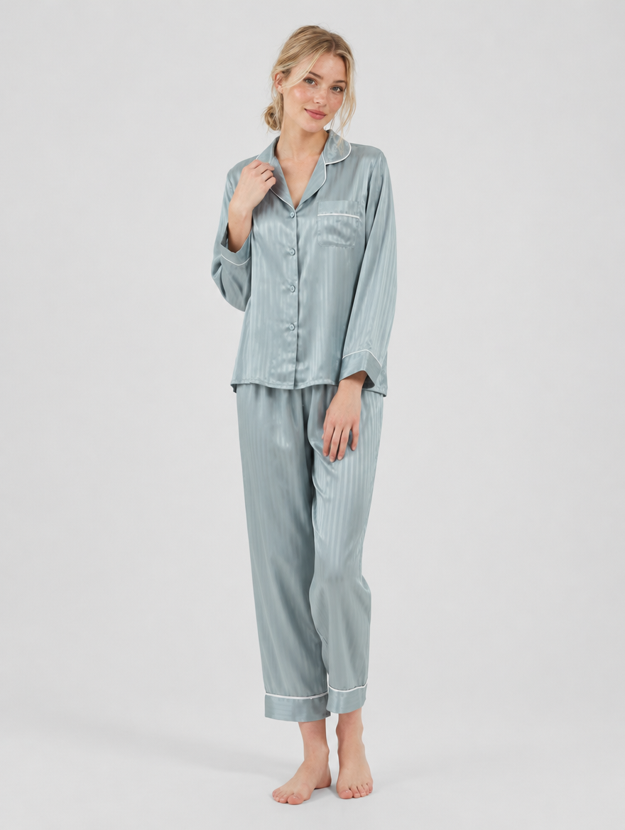 Woman wearing a blue-grey satin button-up pajama set with piping, front view