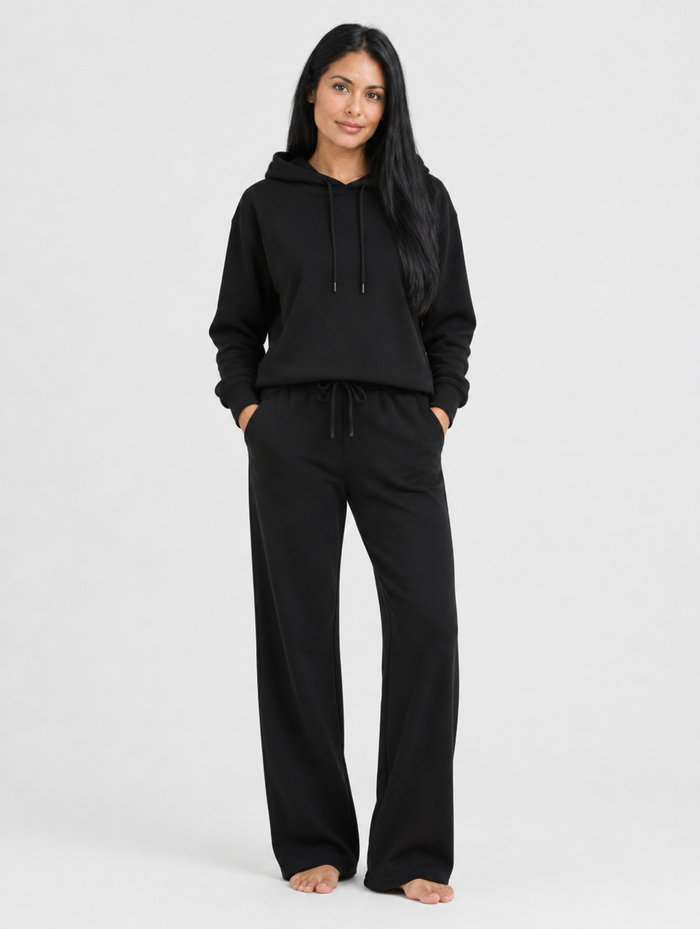 Woman wearing a black hoodie and pants tracksuit set, front view