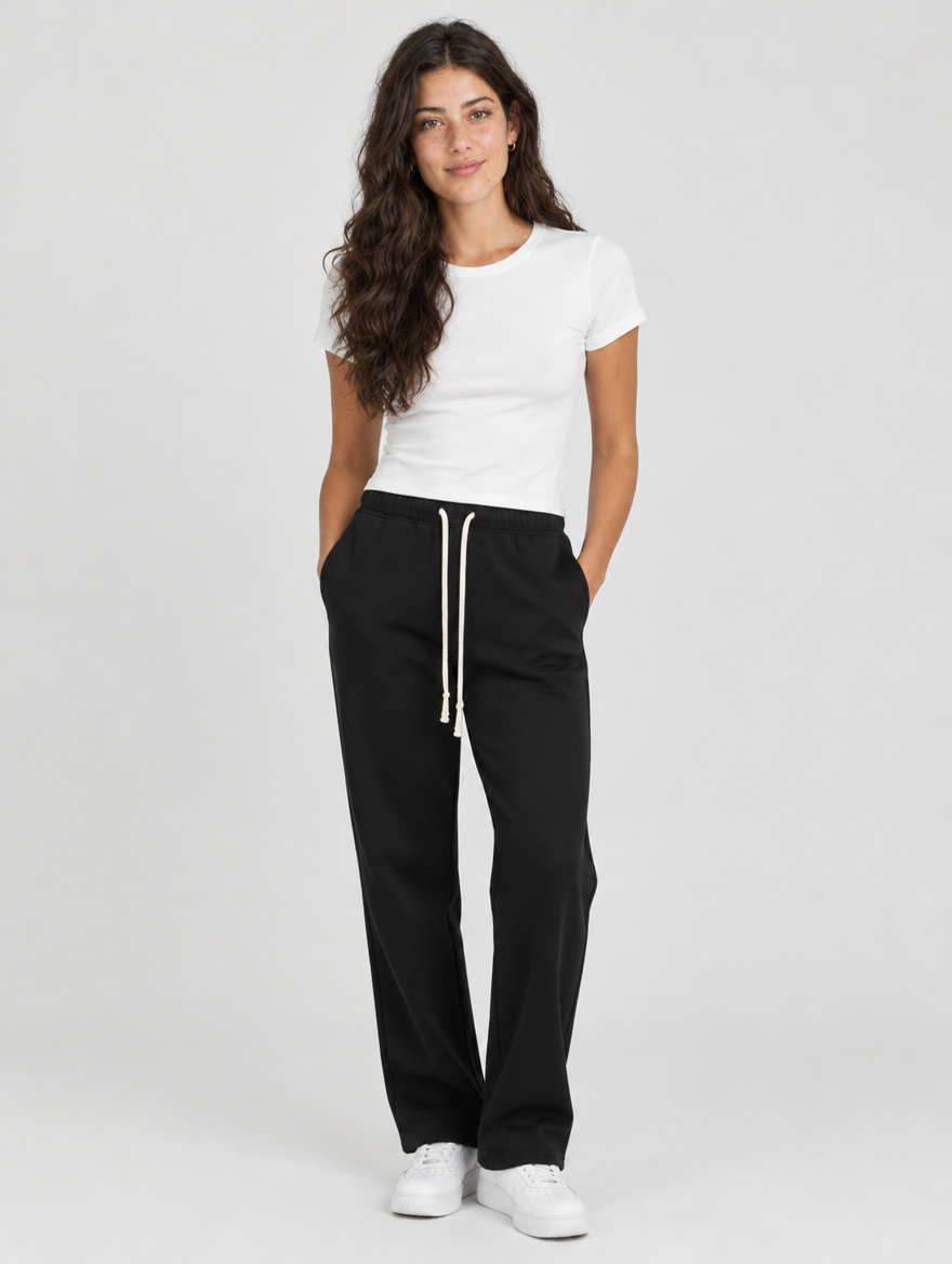 Woman wearing black straight leg drawstring joggers with a white top and sneakers, front view